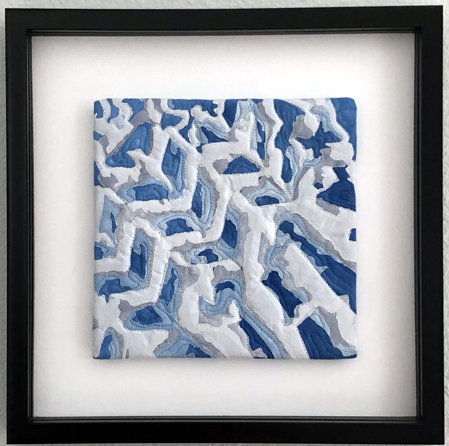 Framed collaged art quilt of tire tracks in snow